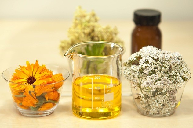 measuring cup with jojoba oil and its flowers